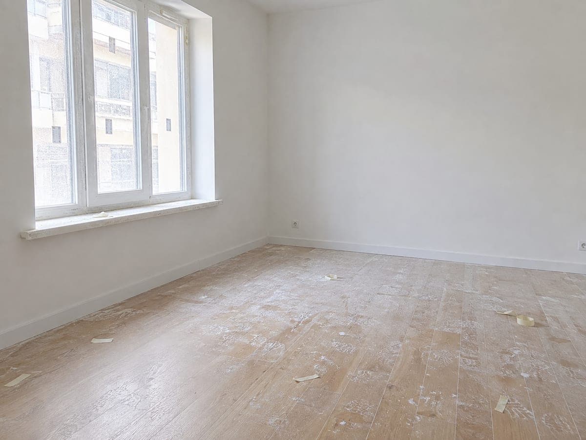 Parquet couvert de plâtre et de résidus après des travaux
